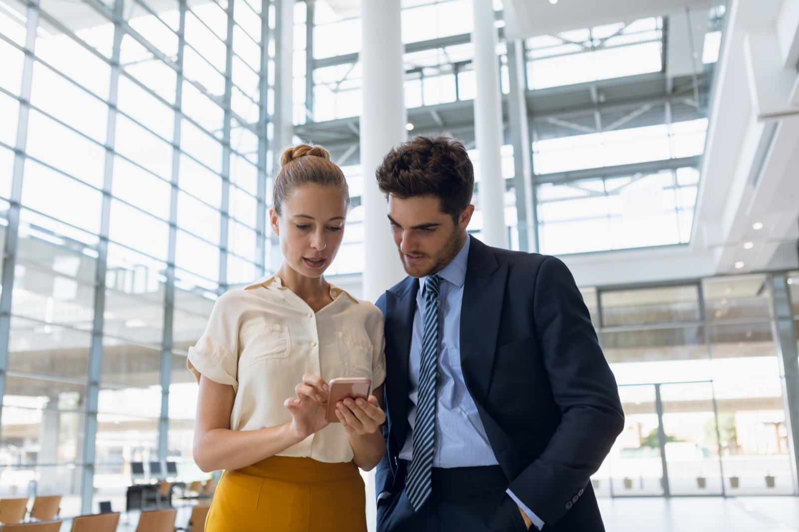 Two professionals sharing a Yipp card with one tap of a phone in a modern office